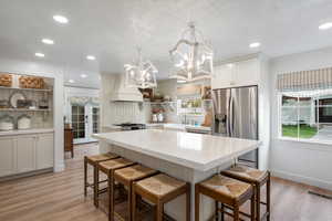 Kitchen featuring a notable chandelier, crown molding, premium range hood, appliances with stainless steel finishes, and visible vents