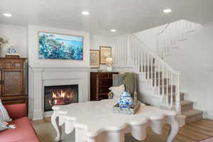 Dining area with stairway, a glass covered fireplace, wood finished floors, and recessed lighting
