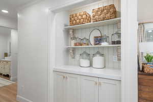 Bar with baseboards, wood finished floors, and recessed lighting