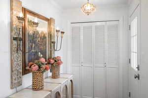 Interior space with washer and clothes dryer, a chandelier, a closet, and crown molding