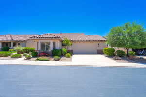 View of front of house featuring a garage, driveway, stucco siding, and a tiled roof