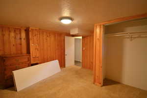 Basement Bedroom 1 - Largest of the 2. featuring a closet, carpet flooring, a textured ceiling, and wooden paneled walls