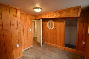 Basement bedroom, wooden paneled walls, and new flooring in room and in closet.