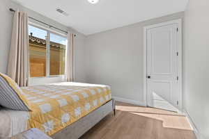 Bedroom with baseboards, wood finished floors, and visible vents