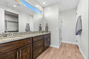 Full bath featuring a sink, a stall shower, visible vents, baseboards, and wood finished floors