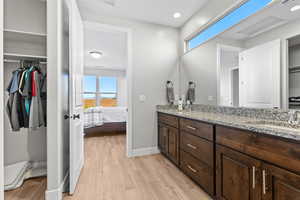 Bathroom with double vanity, wood finished floors, ensuite bathroom, and a sink