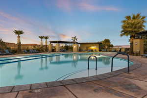 Pool at dusk featuring a community pool and a patio area