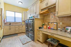 Laundry room featuring light wood-style flooring, a sink, washer and clothes dryer, and cabinet space