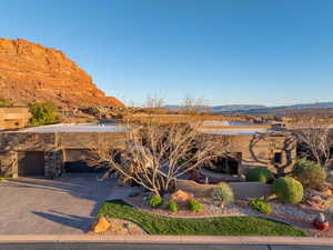 Exterior space with stone siding, driveway, a garage, and a mountain view