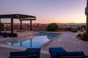 View of pool featuring a pool with connected hot tub, a fenced backyard, a patio, and a mountain view