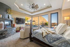 Bedroom featuring ceiling fan, a tray ceiling, a fireplace, visible vents, and recessed lighting