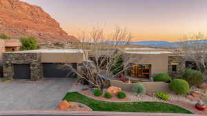Pueblo-style home featuring an attached garage, driveway, stucco siding, and a mountain view