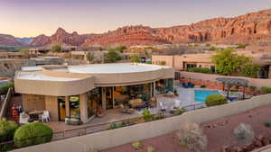 Back of house at dusk with a fenced in pool, fence, stucco siding, a patio area, and a mountain view
