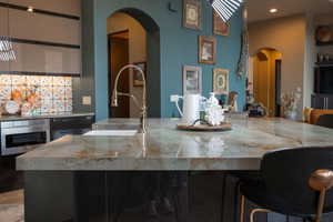 Kitchen featuring recessed lighting, a sink, arched walkways, stainless steel oven, and a breakfast bar area