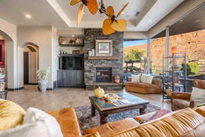 Living area featuring a ceiling fan, visible vents, arched walkways, and a tray ceiling