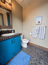 Half bath featuring baseboards, toilet, and vanity