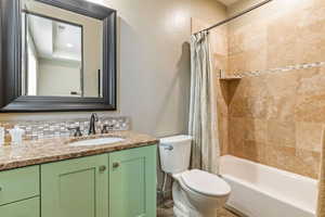 Full bathroom featuring shower / bath combo, vanity, tasteful backsplash, and toilet
