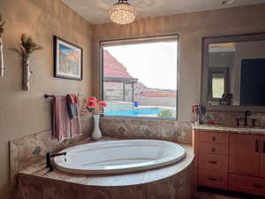 Bathroom featuring a chandelier, a bath, and vanity