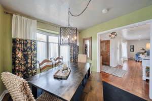 Dining area featuring hardwood / wood-style floors, visible vents, baseboards, and an inviting chandelier