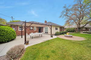 Rear view of property with brick siding, a yard, a patio area, and a chimney
