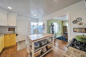 Kitchen with open shelves, light wood finished floors, decorative backsplash, and recessed lighting