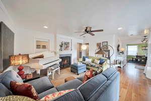 Living area featuring recessed lighting, a ceiling fan, ornamental molding, a lit fireplace, and light wood-style flooring