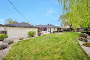 Back of property featuring a lawn, an outbuilding, and a patio