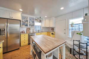 Kitchen with light wood finished floors, a sink, butcher block countertops, open shelves, and appliances with stainless steel finishes