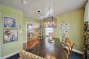 Dining area with baseboards, dark wood-style flooring, and a chandelier