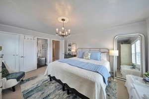 Bedroom with an inviting chandelier, crown molding, and carpet floors