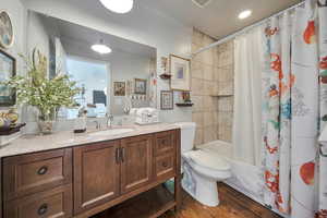 Full bathroom featuring shower / bath combo, wood finished floors, vanity, toilet, and ornamental molding