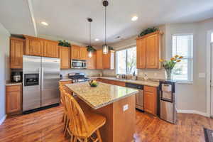 Kitchen featuring a center island, a sink, light wood-type flooring, baseboards, and appliances with stainless steel finishes
