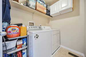 Washroom with washer and clothes dryer, light tile patterned flooring, cabinet space, baseboards, and visible vents