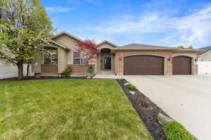 View of front of house featuring a front lawn, driveway, an attached garage, fence, and brick siding