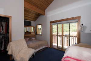 Carpeted bedroom with high vaulted ceiling, a closet, wood ceiling, beam ceiling, and access to exterior