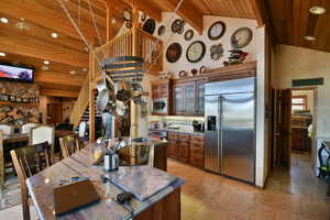 Kitchen featuring recessed lighting, built in appliances, wooden ceiling, glass insert cabinets, and high vaulted ceiling