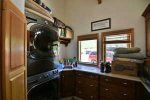 Clothes washing area with cabinet space and stacked washer and dryer