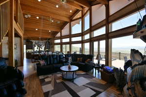 Living area with recessed lighting, wood finished floors, a water view, and high vaulted ceiling