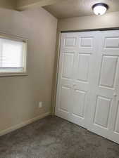 Unfurnished bedroom with dark colored carpet, a textured ceiling, and a closet