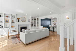 Living area featuring recessed lighting, stairs, a decorative wall, a fireplace, and ornamental molding