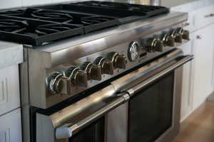 Interior details featuring tasteful backsplash, double oven range, and wood finished floors