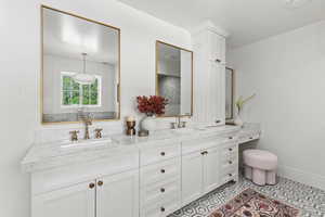 Bathroom featuring double vanity, tile patterned flooring, baseboards, and a sink