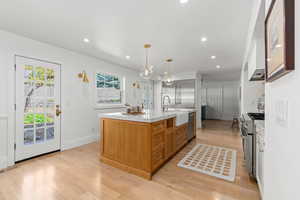 Kitchen featuring light wood-type flooring, light countertops, a sink, and appliances with stainless steel finishes