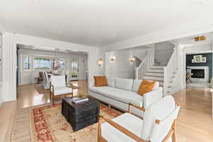 Living room with a decorative wall, crown molding, and stairs