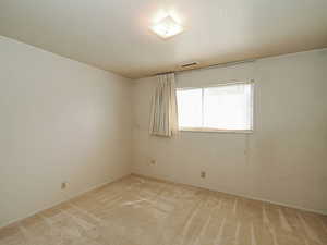 Empty room featuring light colored carpet and baseboards