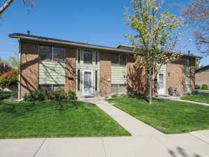 Bi-level home featuring a front yard and brick siding