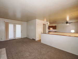 Unfurnished living room with visible vents, a ceiling fan, and carpet floors