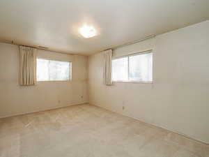 Empty room with visible vents, a wealth of natural light, light colored carpet, and baseboards