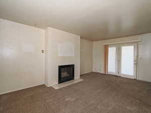 Unfurnished living room with carpet floors and a fireplace with flush hearth