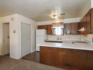 Kitchen featuring white appliances, light countertops, a peninsula, and under cabinet range hood